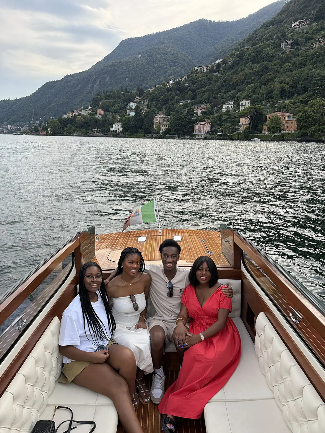 Sharonda and friends on a wooden boat on a lake surrounded by mountains