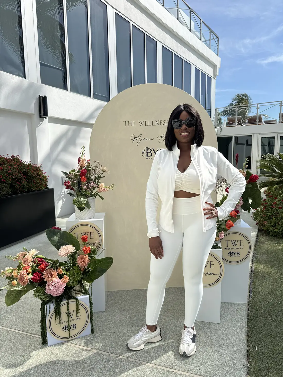 Sharonda in an all-white set at a wellness event, surrounded by flowers