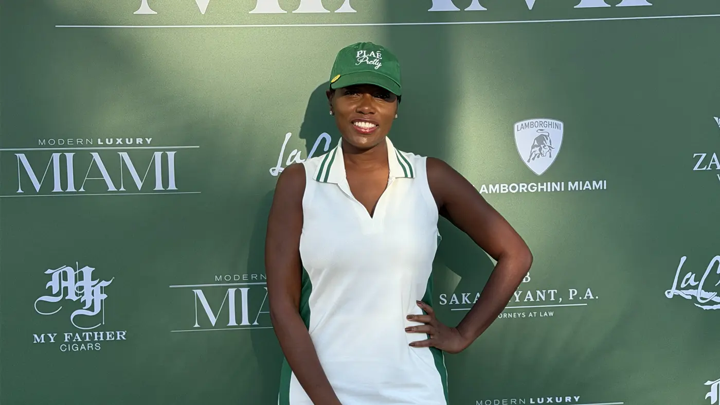 Sharonda smiling in a green cap and white golf dress at a Modern Luxury Miami golf event