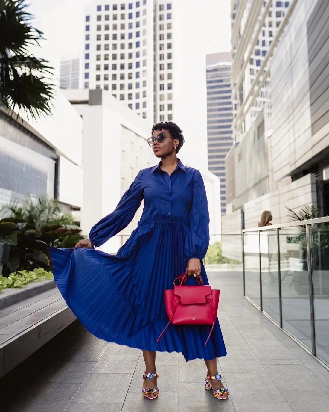 Sharonda twirling in a cobalt blue dress with a red handbag